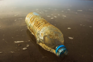 Bottiglia di plastica abbandonata sulla riva del mare